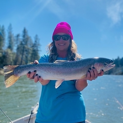 Another view of woman holding up fish caught on lake.